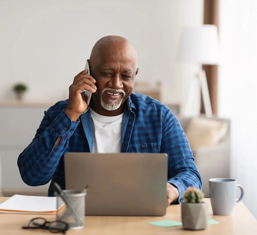 Smiling man using laptop and phone