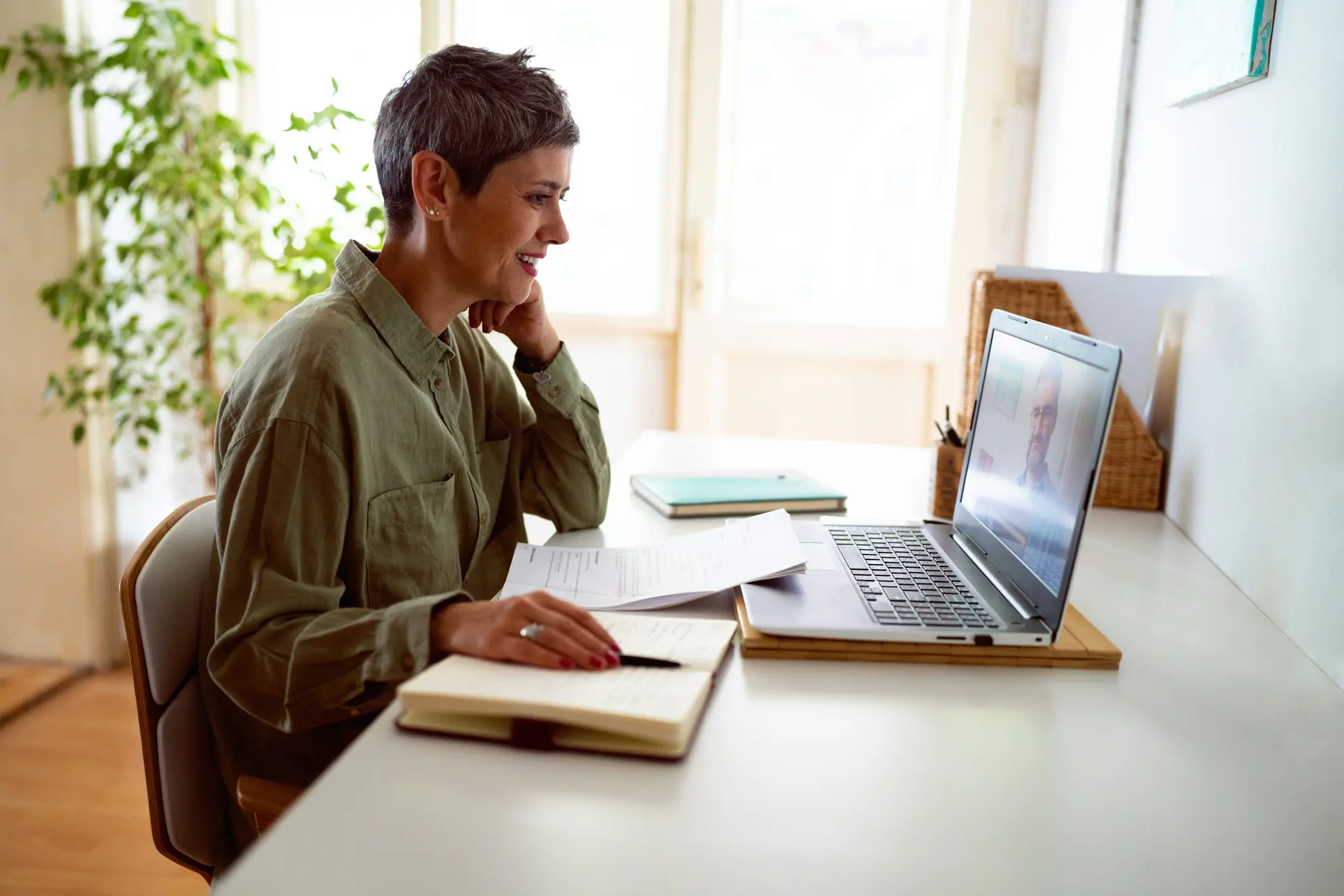 A man working on a laptop and taking notes.