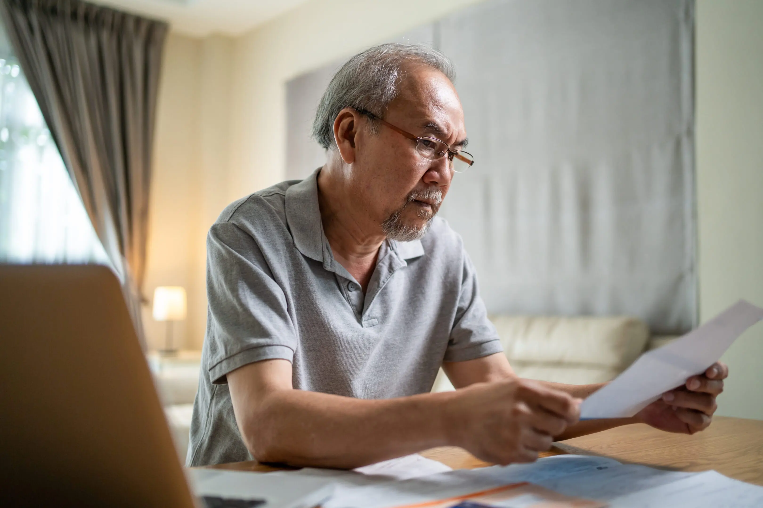 Depressed Asian Senior male feeling worried about financial problem. Stressed desperate elderly older man looking frustrated to paperwork and bills think of money debt, budget loss, bankruptcy at home