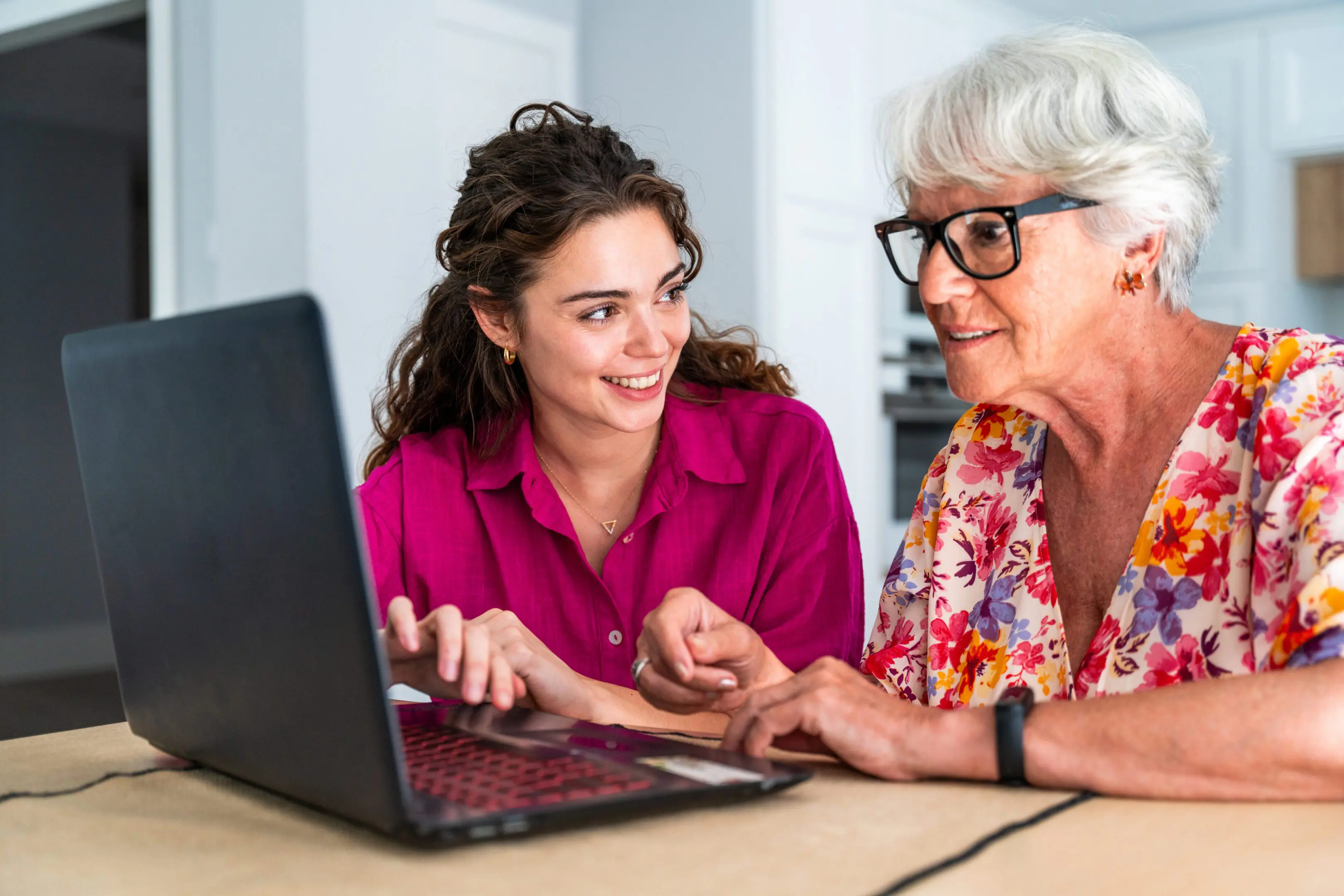 Beautiful grandmother and granddaughter together at home teaching how to use computer - Cheerful granma and nephew spending quality time together