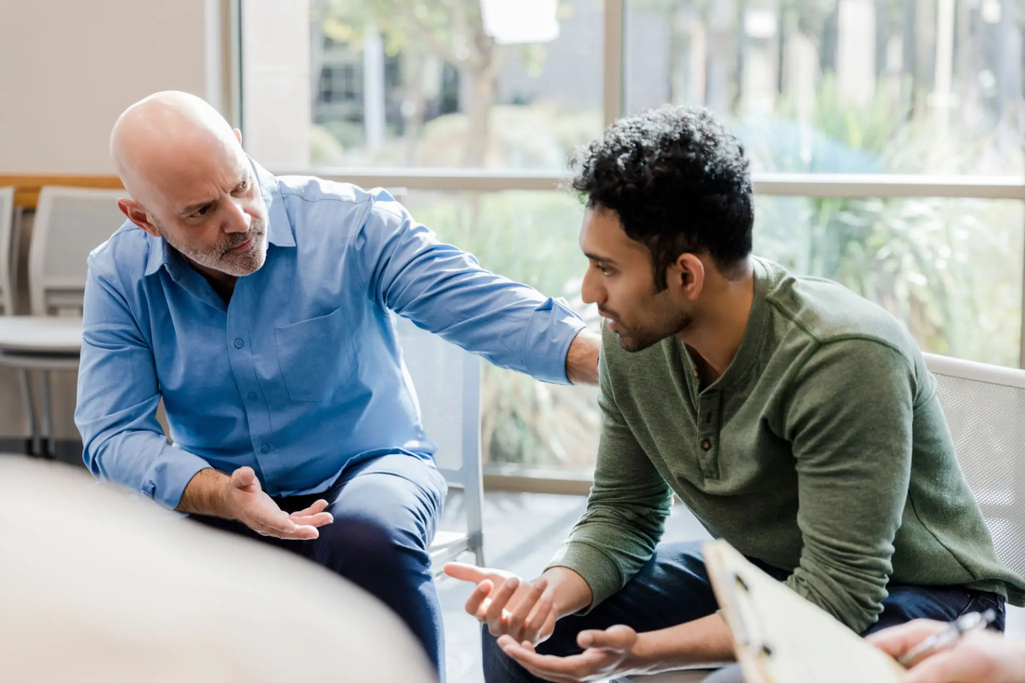 An older man listens attentively to a younger man during a thoughtful conversation.