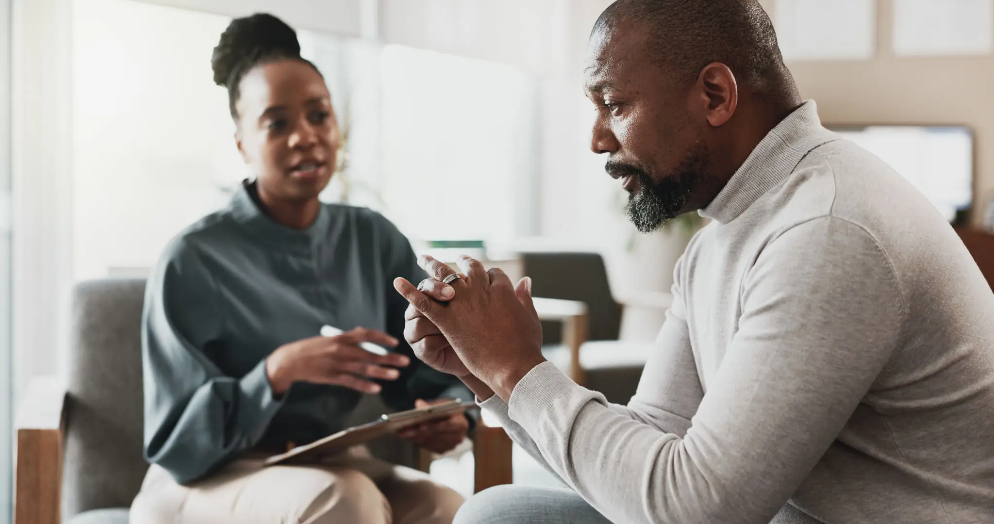 A man and woman engaged in a serious conversation indoors.
