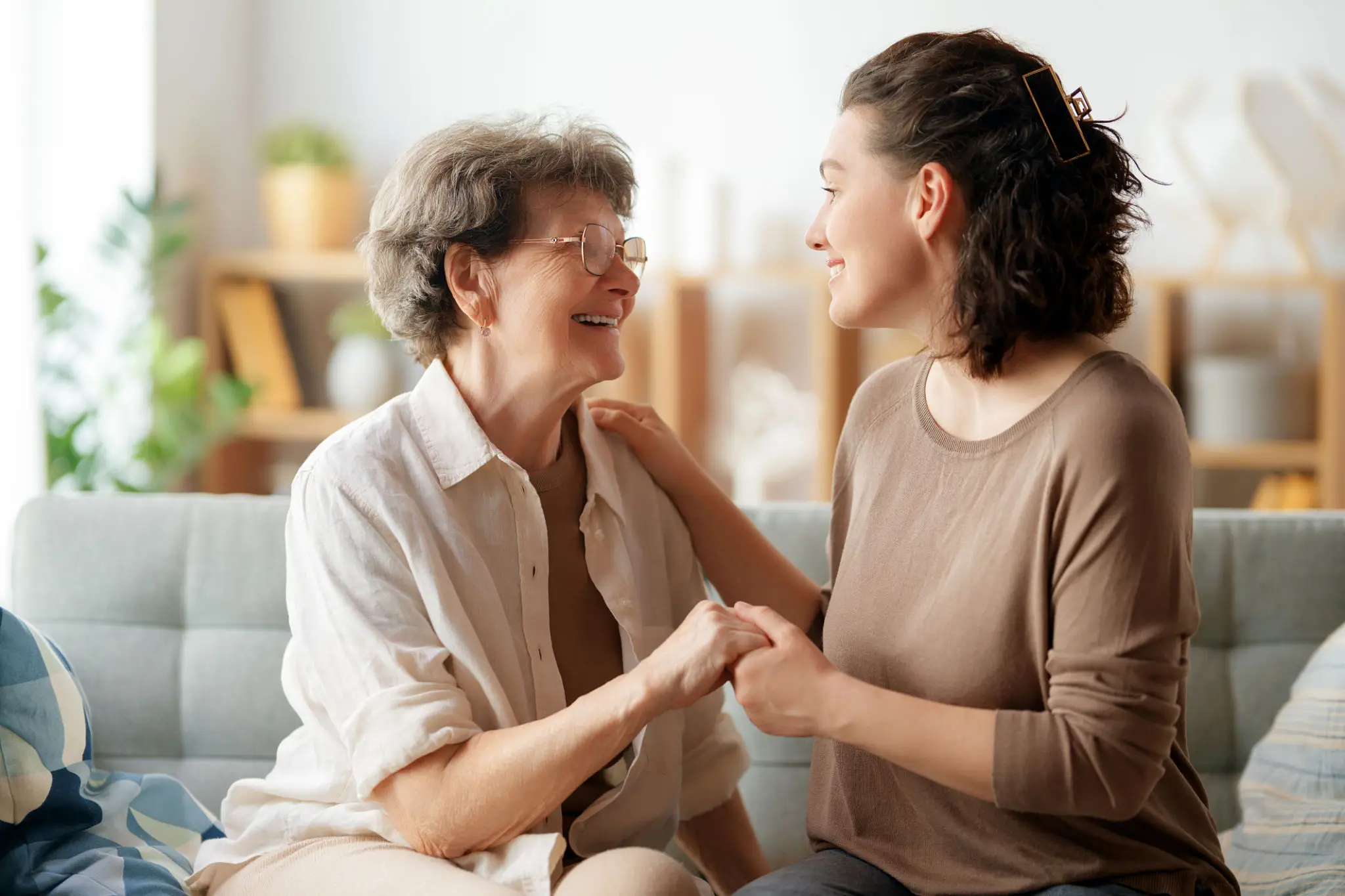 A warm moment between an elderly woman and a younger woman holding hands.