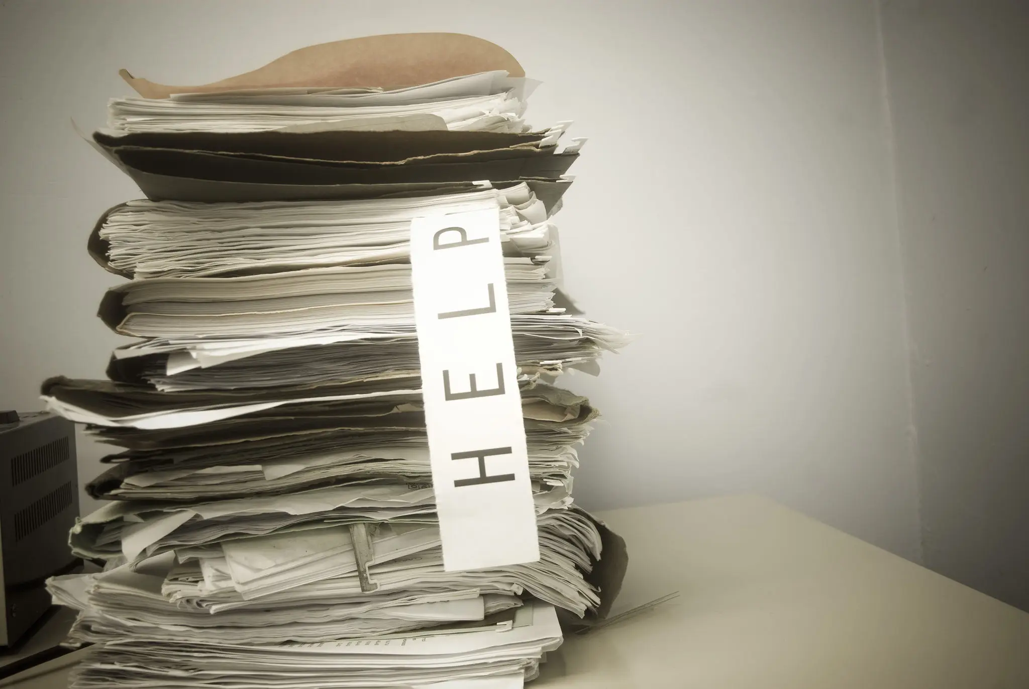 A thick stack of papers with a 'HELP' note sticking out.