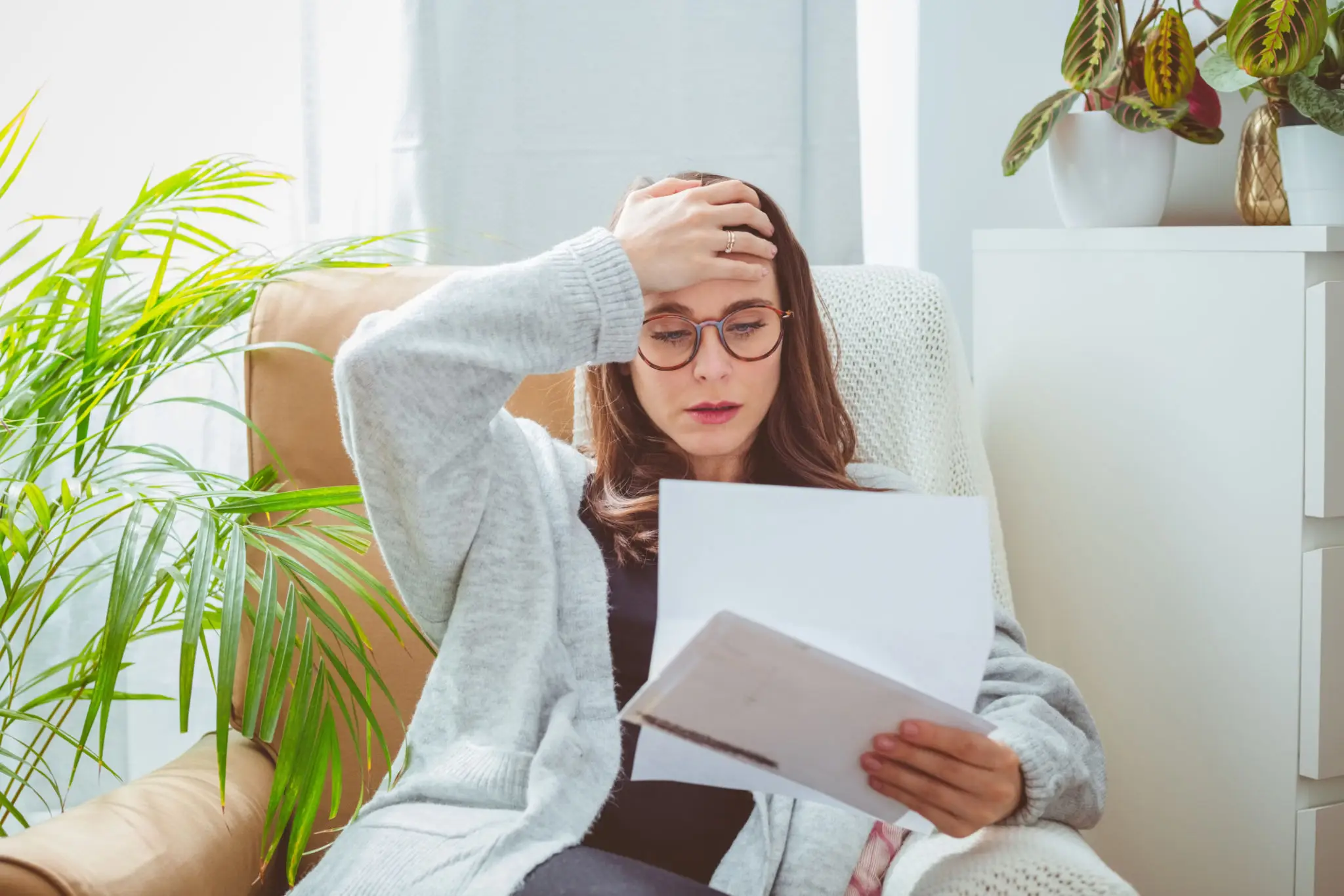 Woman looking stressed reading paperwork at home.