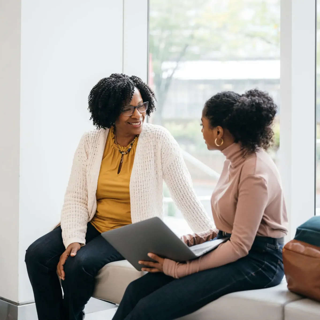 Two women engaged in a friendly conversation indoors.