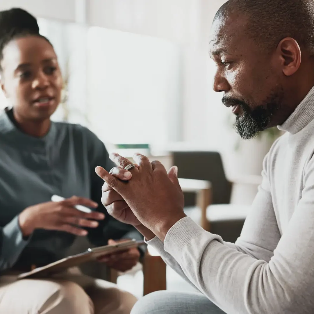 A man and woman engaged in a serious conversation indoors.