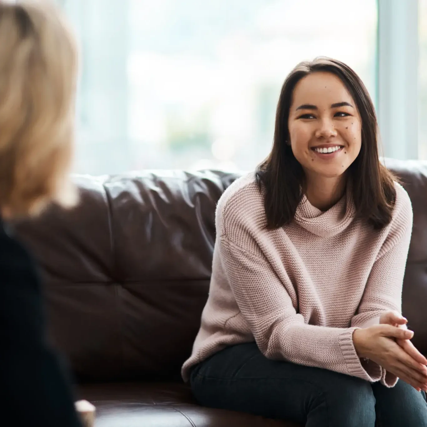 Two women engaged in a friendly conversation on a couch.